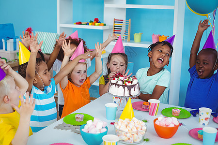 享受生日派对的兴奋儿童庆典快乐蛋糕男性微笑糖果女性帽子桌子食物图片
