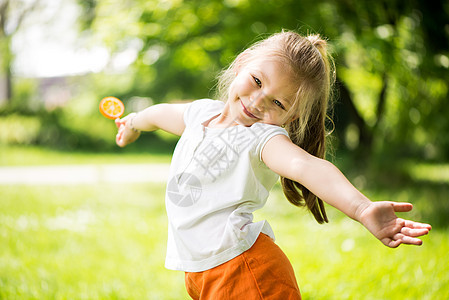 公园中的小女孩童年喜悦乐趣双臂水平金发小姑娘微笑孩子们绿色图片