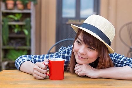 穿着帽子的女士坐在户外 喝热饮放松女性享受食物眼睛咖啡店咖啡饮料杯子女孩巧克力图片