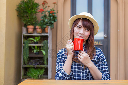 穿着帽子的女士坐在户外 喝热饮放松黑发饮料享受杯子咖啡店女孩眼睛巧克力食物女性图片