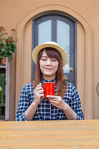 穿着帽子的女士坐在户外 喝热饮放松食物眼睛饮料杯子享受女孩咖啡巧克力女性黑发图片
