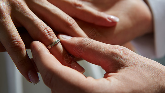 新郎把戒指戴在新娘的手指上婚姻金子庆典丈夫裙子花束妻子浪漫男性仪式图片