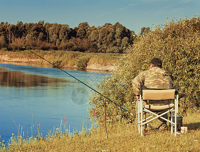 在河岸上钓鱼的渔夫淡水男人行动闲暇爱好活动部分森林阳光娱乐背景图片