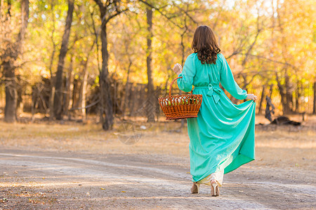 一个穿着长裙的女孩在路上走着 手里拿着一个篮子图片
