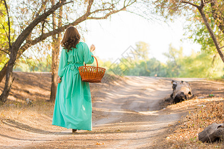 一个穿着长裙的姑娘拿着篮子 正在路上 走到远处图片