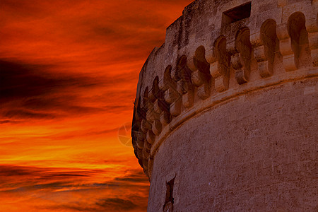 日落天空下古老城堡塔的废墟图片
