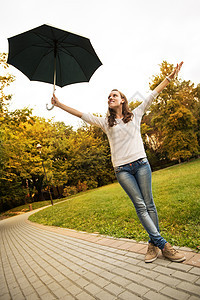 带雨伞的年轻妇女女性成人幸福快乐微笑喜悦公园季节手臂图片