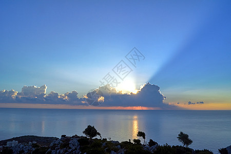 地中海上空的太阳升起石头植物地平线天空海岸图片