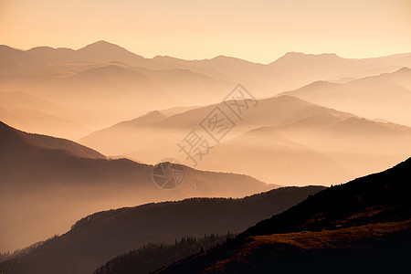 日落时迷雾山丘的风景图片