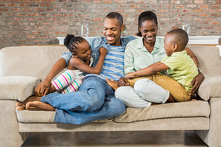 幸福的一家人一起在沙发上摆姿势家庭生活男生公寓拥抱女儿女性长椅闲暇女孩童年图片