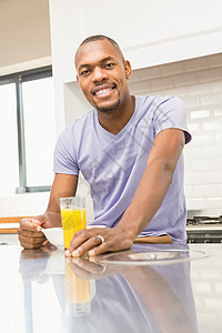 男人在吃早餐时随便开心橙汁微笑男性咖啡果汁阅读饮料家庭生活厨房面包图片