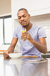 男人在吃早餐时随便开心饮料微笑谷物面包咖啡阅读玻璃男性橙汁桌子图片