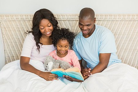 和女儿在床上看书的一对漂亮的夫妻女士快乐家庭父亲男人卧室家庭生活女性感情房子图片