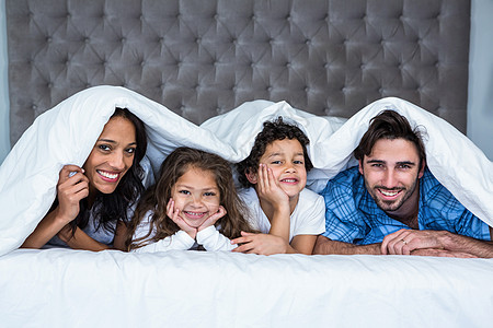 在毯子下幸福的家庭公寓母亲快乐闹钟享受儿子闲暇男人女士女儿图片