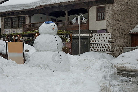 Bansko镇的雪冬广场 有古老的房子 葡萄藤和雪人图片