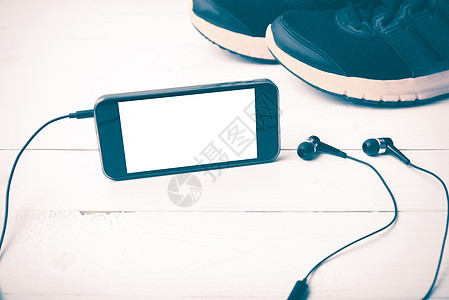 运动鞋和电话老旧风格白色音乐手表运动手机毛巾木头技术跑步健身房背景图片