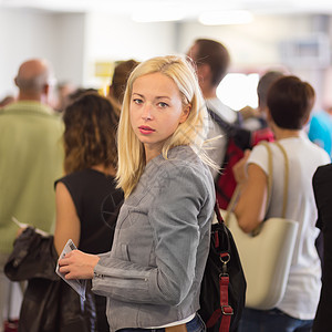 年轻的金发卡布西女人排队等着呢队列旅行航班工作过境挫折人群飞机场运输服务背景图片