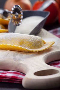 切片板上的小托尔塔利尼木头洋葱美食蔬菜烹饪车轮面团面条糕点轮黄色图片