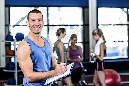 在剪贴板上写字的肌肉训练器运动服男性健身房健身健身室青少年闲暇微笑女士运动员图片