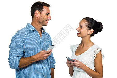 微笑的情侣持有智能手机 互相看着对方图片