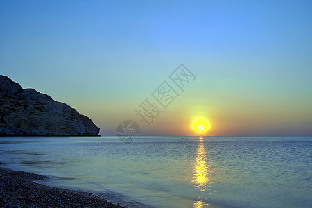 地中海上空罗得斯岛的海面日出天空岩石卵石地平线海岸石头太阳反射海滩图片