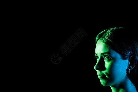 美丽的年轻女人的脸 在蓝色和绿色的灯光下图片