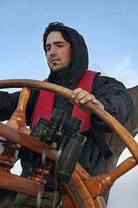 年轻水手驾驶高船木头成人活动甲板座舱人员假期游艇舵手车轮图片