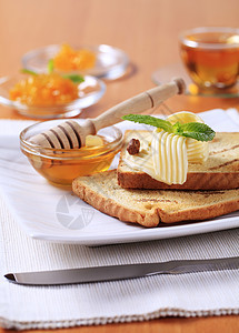甜甜早餐蜂蜜餐巾小吃正方形杯子黄油盘子白色橙子面包图片