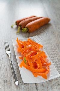 白盘上的胡萝卜沙拉木头绿色沙拉小吃植物橙子面条白色芝麻午餐图片