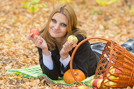 年轻女孩躺在秋林的地毯上 手里拿着两个苹果 在AKY图片