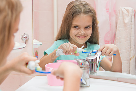 快乐的小女孩挤牙膏 从牙刷上一根管子上的牙膏图片