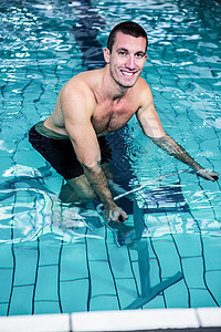 在游泳池里骑车的合适人竞技自行车护理男性身体微笑休闲有氧运动运动水池图片