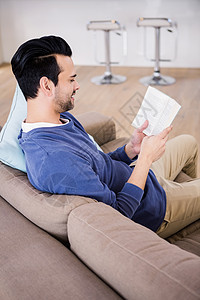 帅哥在沙发上读书枕头家庭生活专注休息室衬衫休闲公寓客厅男性男人图片