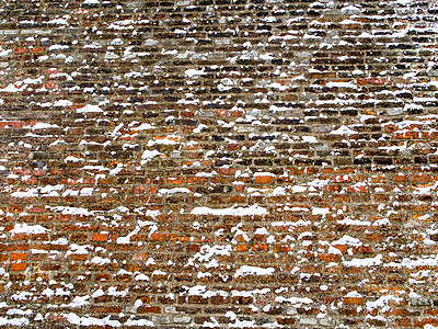 覆盖雪花的宽厚红砖墙图片
