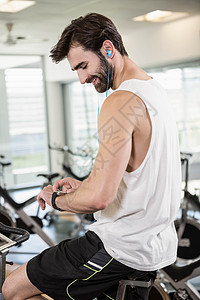 使用智能手表 骑着运动自行车的微笑者训练健身房健身室活动微笑毛巾移动力量护理男性图片