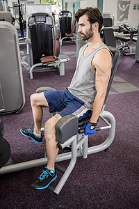 重点男子用称重机械处理腿部男人蓝色背心肌肉专注起重运动力量健身房运动服图片
