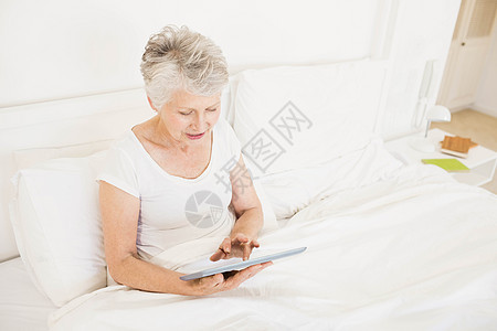 使用平板药的微笑妇女流金退休家庭房子女性电脑棉被床头柜滚动坐垫图片