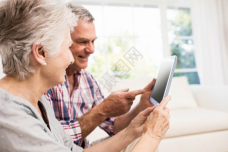 使用平板牌手微笑的老年夫妇住所电脑闲暇男人快乐女性女士退休客厅窗户图片