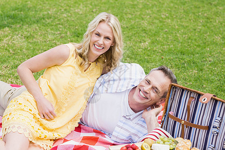 快乐的情侣野餐篮子软垫女性夫妻草地快乐男性闲暇绿地浅色图片