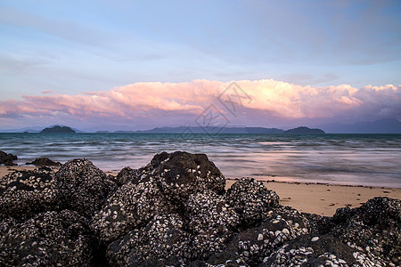 傍晚海滩附近的石块季节海景热带日落蓝色岩石海洋地平线海浪场景图片
