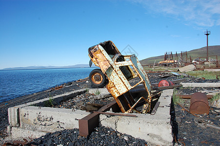 旧的破旧生锈废弃汽车倒在海滨图片