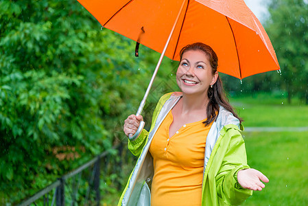 美丽的女孩 有明亮的橙色雨伞图片