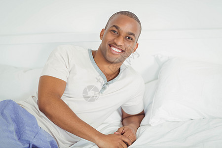 帅哥躺在床上黑色枕头房子棉被家庭坐垫微笑男性卧室床头背景图片