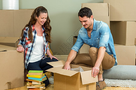 年轻夫妇在新房子里拆包装箱的箱子纸板盒房地产休闲屋主女士搬迁住房情人家庭快乐图片
