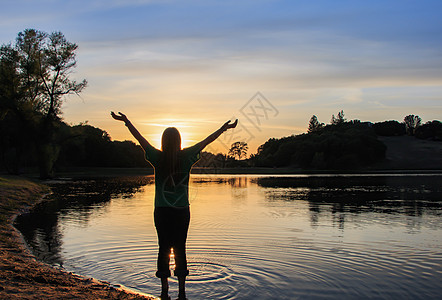 以举手观看日落的女童冥想青年祷告女性海滩树木爬坡蓝色身体自由图片