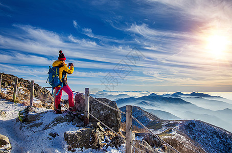 在山峰顶用智能手机拍照的年轻女子徒步旅行者游客女性太阳镜探索运动太阳自拍首脑动机图片