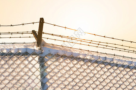 日落时有雪的刺铁丝网栅栏力量监狱天空自由障碍黄色安全金子边界国家图片