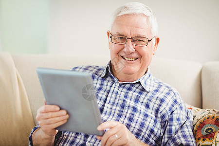 高级男子使用数字平板电脑阅读老年人老年网络闲暇微笑男性服装住所公寓图片