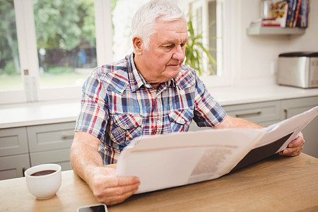 高年男子阅读报纸家庭房子杯子男人住所退休来源厨房服装公寓图片
