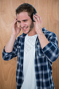 英俊男人用耳机听音乐姿势衣服男性享受毡帽快乐喜悦娱乐性服装商业图片